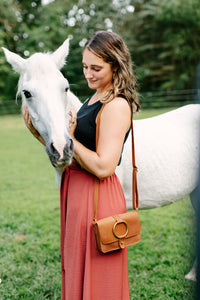 A woman gently pets a beautiful white horse in a grassy field.
