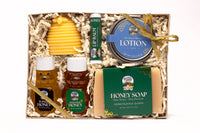 Unwrap a luxurious honey gift set featuring tupelo and wildflower honey, beeswax lotion bar, honey lip balm, and honeysuckle honey soap, all beautifully arranged.
