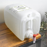 A large container of Rustic Strength Floor Cleaner Concentrate with a dispenser rests on a wooden table.
