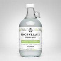 View showcases a glass jug of Rustic Strength floor cleaner concentrate featuring bergamot and cypress essential oils.
