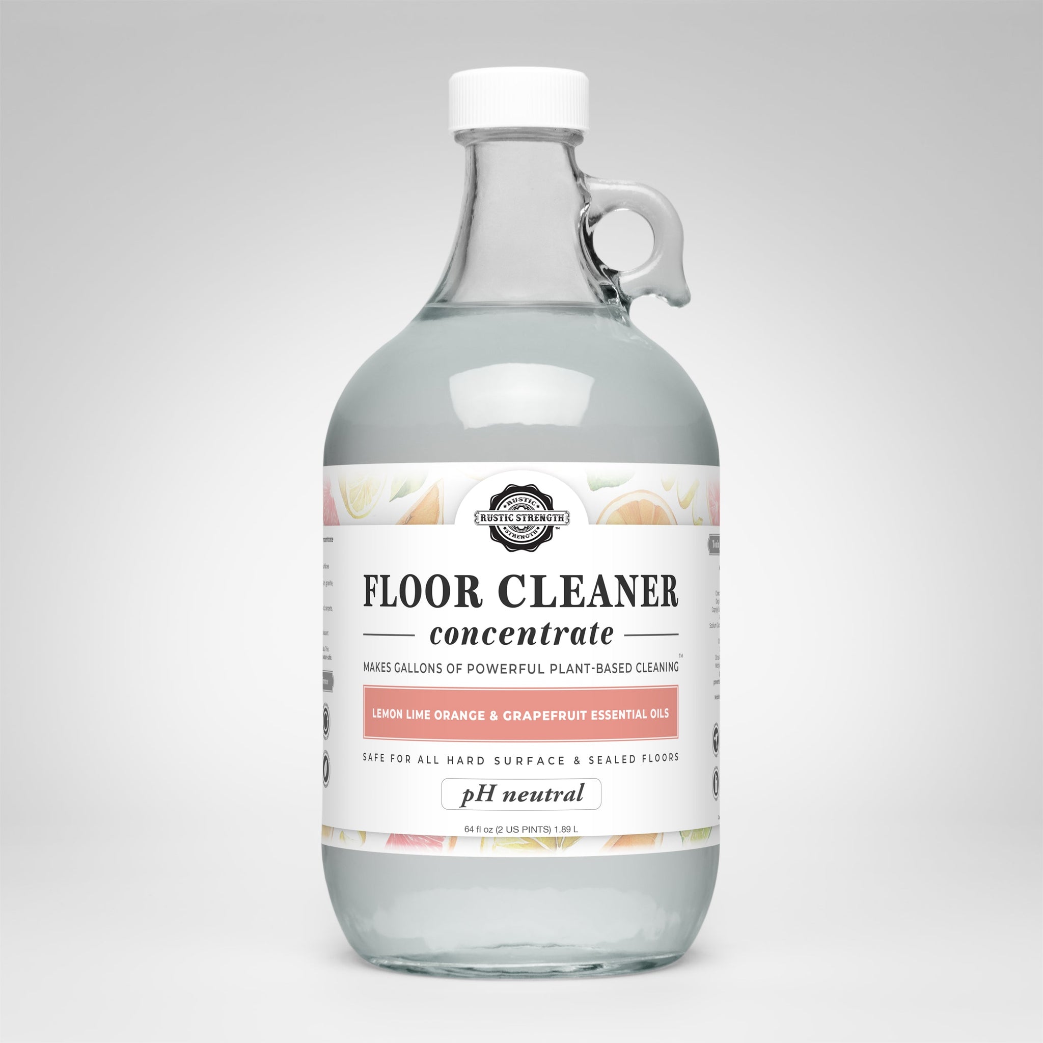 A glass jug displays the label for Rustic Strength plant-based floor cleaner concentrate with lemon, lime, orange, and grapefruit essential oils.