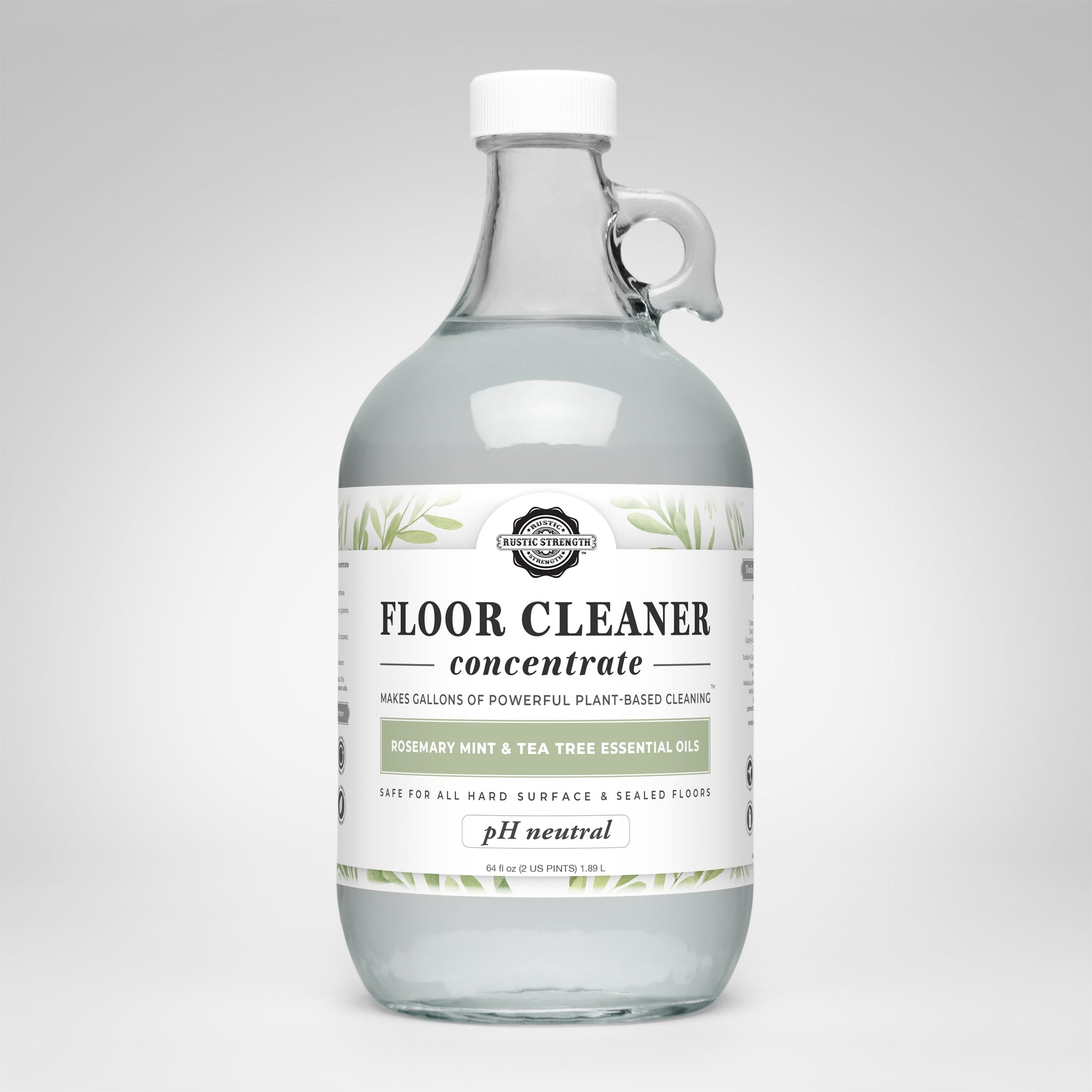 A glass jug displays Rustic Strength Floor Cleaner concentrate, highlighting its plant-based formula with rosemary, mint, and tea tree essential oils.