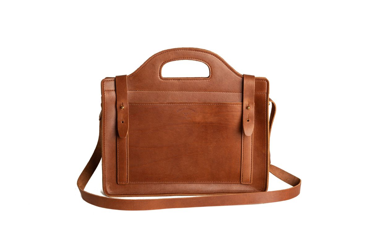 A brown leather satchel handbag featuring a top handle and shoulder strap sits against a white background.

