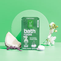 Green Llama presents its compostable lavender bathroom cleaner refill, displayed with a coconut wedge and white flowers on a mint green background.

