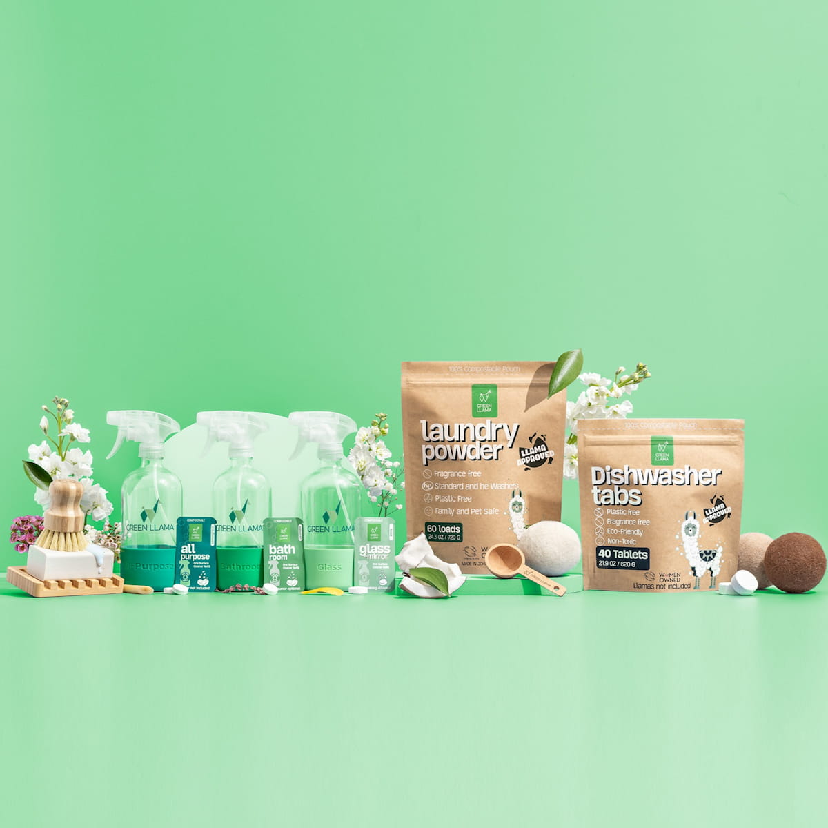 Green Llama brand displays their eco-friendly cleaning products, including all-purpose cleaner, laundry powder, and dishwasher tabs, against a fresh green backdrop.
