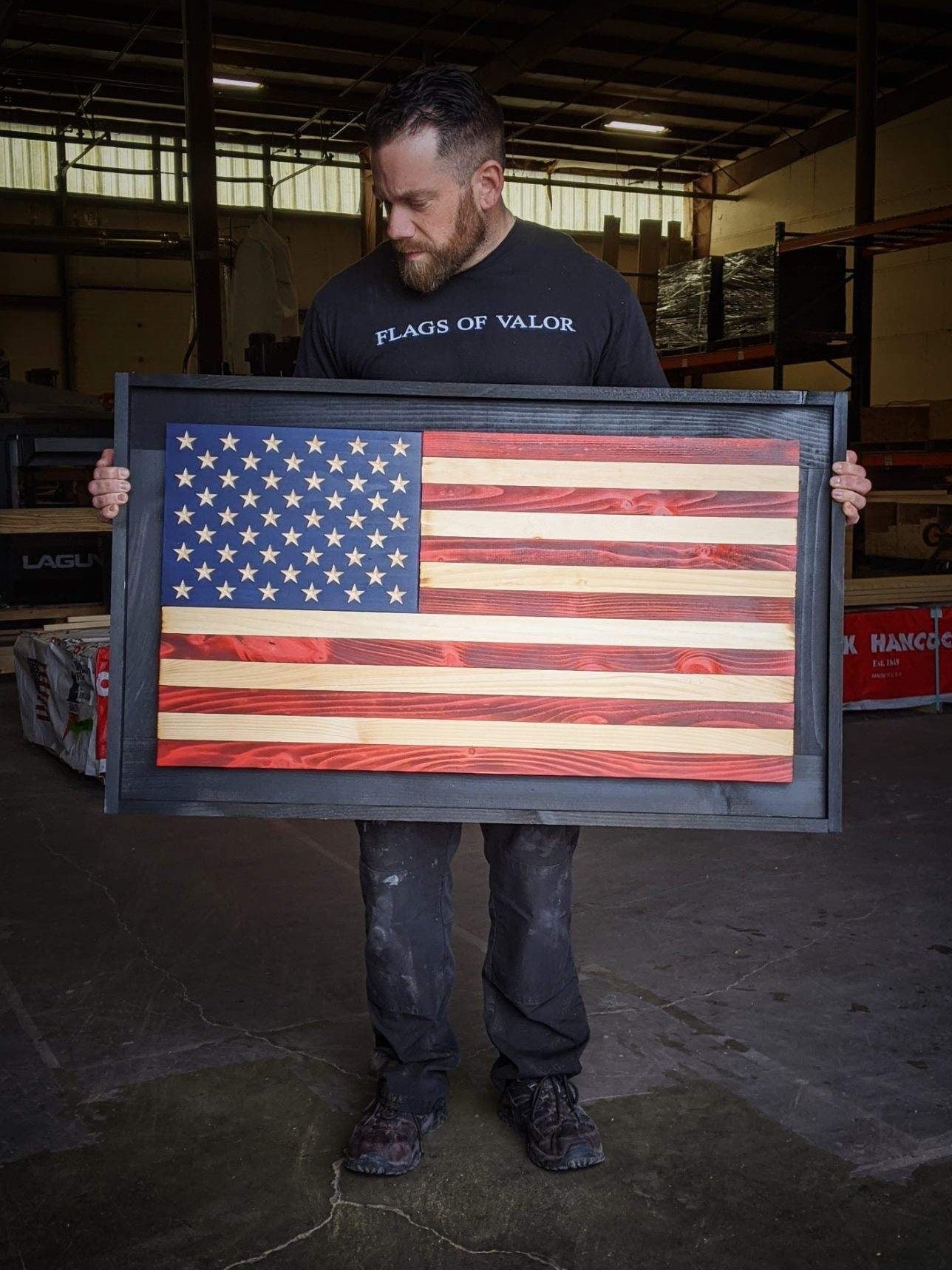 Person holding a wooden American flag in a warehouse setting