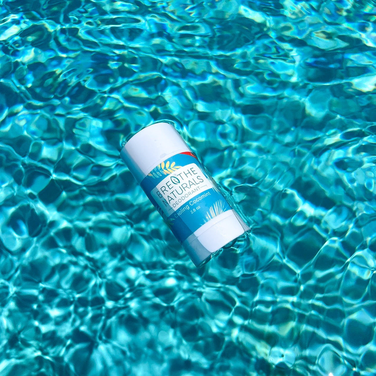 Breathe Naturals deodorant floats serenely on the surface of shimmering turquoise water.
