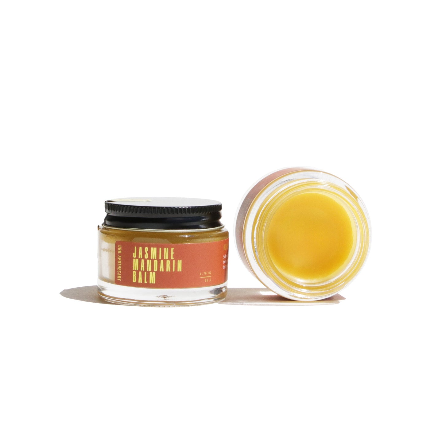 Two jars of Urb Apothecary Jasmine Mandarin Balm sit on a white surface.
