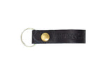 Showcases the stylish "Urban Southern" black leather keychain with a brass rivet and silver keyring.
