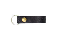 Showcases the stylish "Urban Southern" black leather keychain with a brass rivet and silver keyring.
