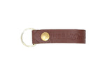 A brown leather keychain features the "Urban South" logo and a silver key ring.
