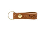 Showcases a stylish leather keychain featuring the "Urban South" logo and a gold key ring.
