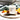 Candle labeled 'Lemongrass + Tangerine' on a marble surface with orange slices.