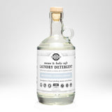 Rustic Strength presents their mama and baby safe, unscented laundry detergent in a clear glass jug with a wooden stopper.
