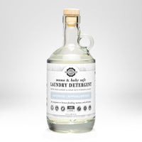 Rustic Strength presents their mama and baby safe, unscented laundry detergent in a clear glass jug with a wooden stopper.
