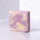 A swirl of lavender and cream colors the surface of this artisanal handmade soap bar.
