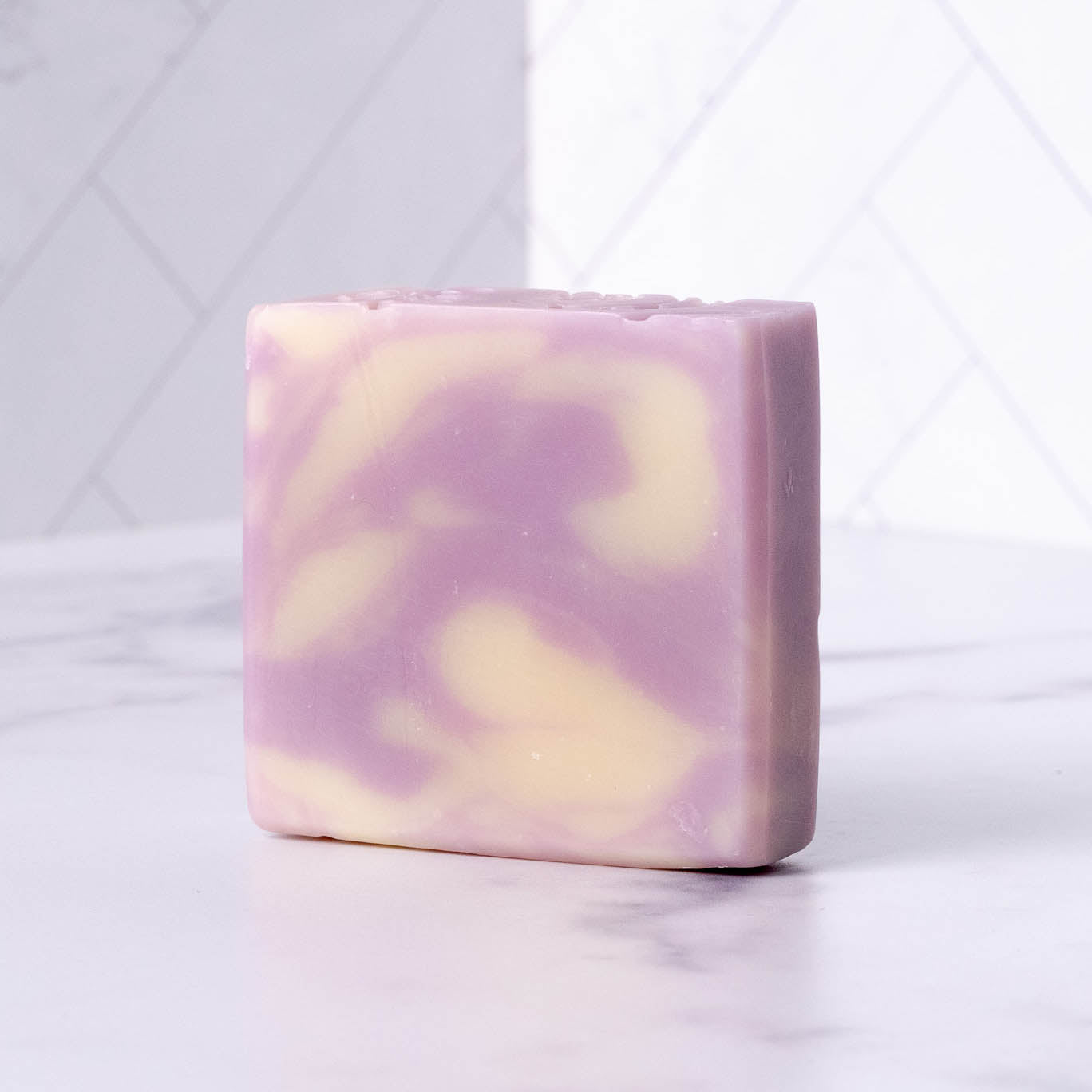 A swirl of lavender and cream colors the surface of this artisanal handmade soap bar.
