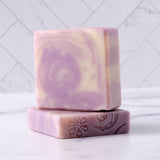 Handmade lavender soap bars display a floral design and swirling patterns.
