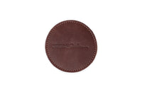 Close-up shows a round, stitched leather coaster with the "Urban Southern" logo embossed.
