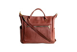 Displays a stylish brown leather tote bag with shoulder strap and multiple pockets.
