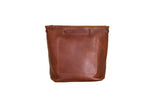A brown leather bucket bag with a square pocket presents a minimalist and stylish design.
