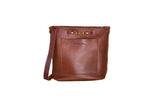 Displaying a stylish brown leather bucket bag with a front pocket and gold-colored hardware.
