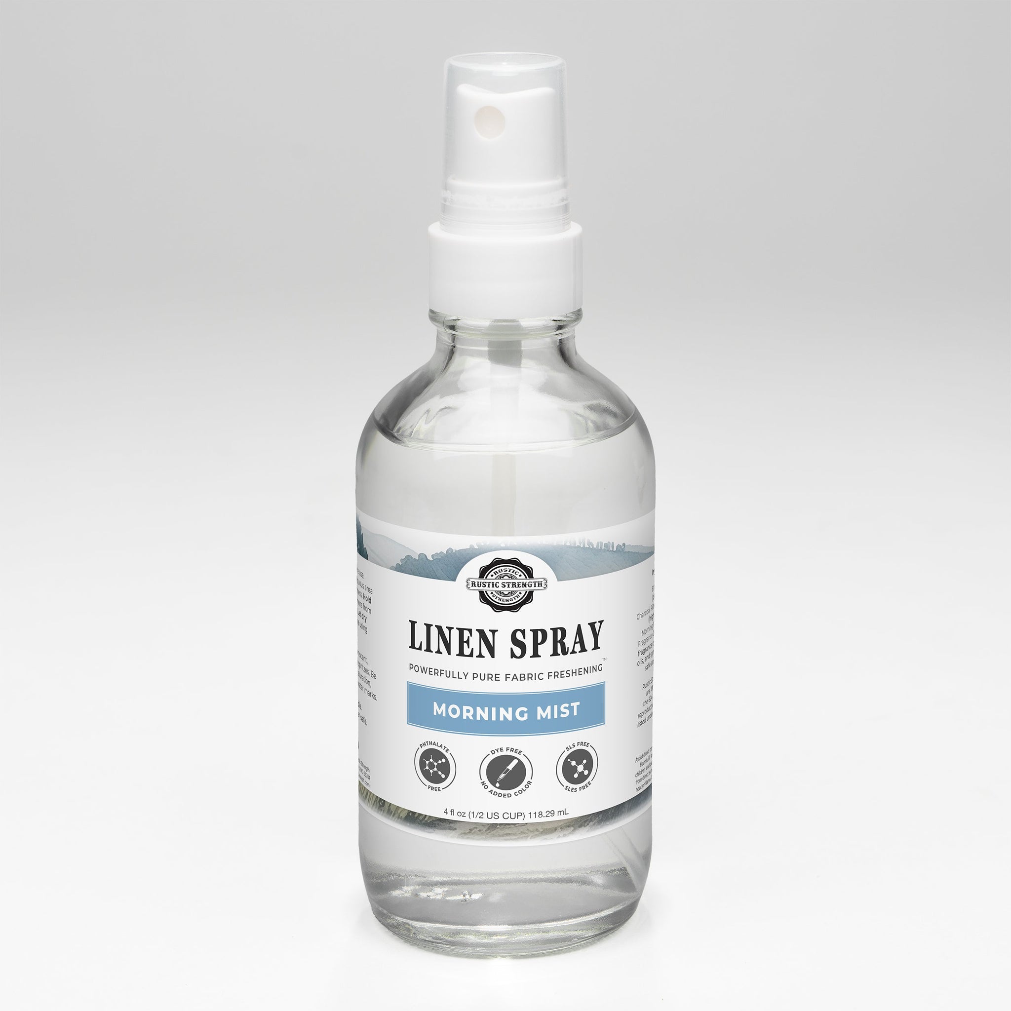 A clear bottle displays Rustic Strength Linen Spray in Morning Mist scent, promising powerfully pure fabric freshening.