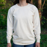 Woman models a sustainable, organic cotton long-sleeve tee shirt outdoors.
