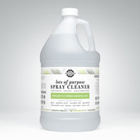 A large jug displays the label for Rustic Strength Lots of Purpose Spray Cleaner, highlighting its bergamot and cypress essential oils.
