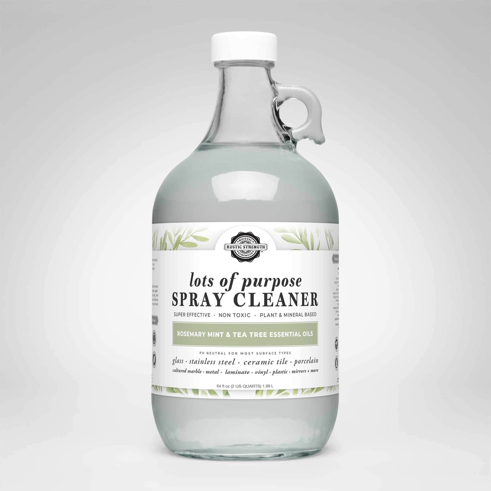 Rustic Strength's lots of purpose spray cleaner, scented with rosemary, mint, and tea tree essential oils, sits in a clear glass jug with a handle.
