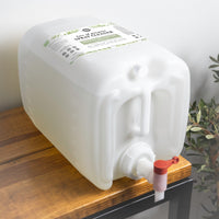 A large container of Rustic Strength multi-purpose spray cleaner with rosemary mint and tea tree essential oils rests on a wooden shelf.