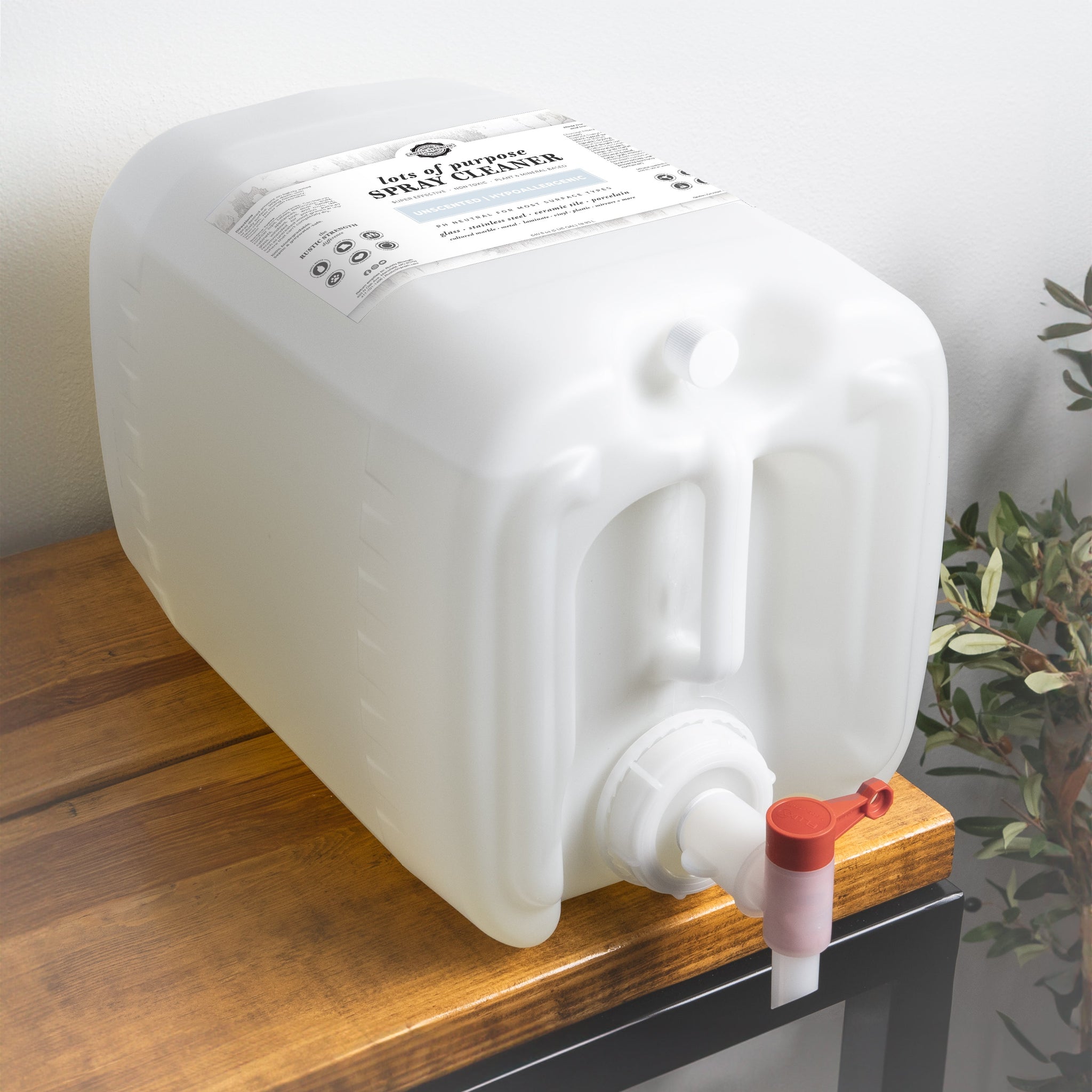 A large container of Rustic Strength multi-purpose spray cleaner sits on a wooden shelf, ready for eco-friendly cleaning.
