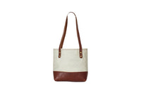 Showcases a stylish canvas tote bag with leather accents against a clean white background.
