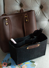 Organize your tote with a felt purse organizer and leather handbag from Urbana Sacs, pictured with sunglasses and a floral notebook.
