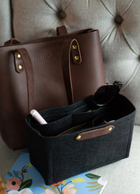 Organize your tote with a felt purse organizer and leather handbag from Urbana Sacs, pictured with sunglasses and a floral notebook.
