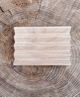 A handcrafted wooden soap dish sits on a rustic tree stump, showcasing natural wood grain.
