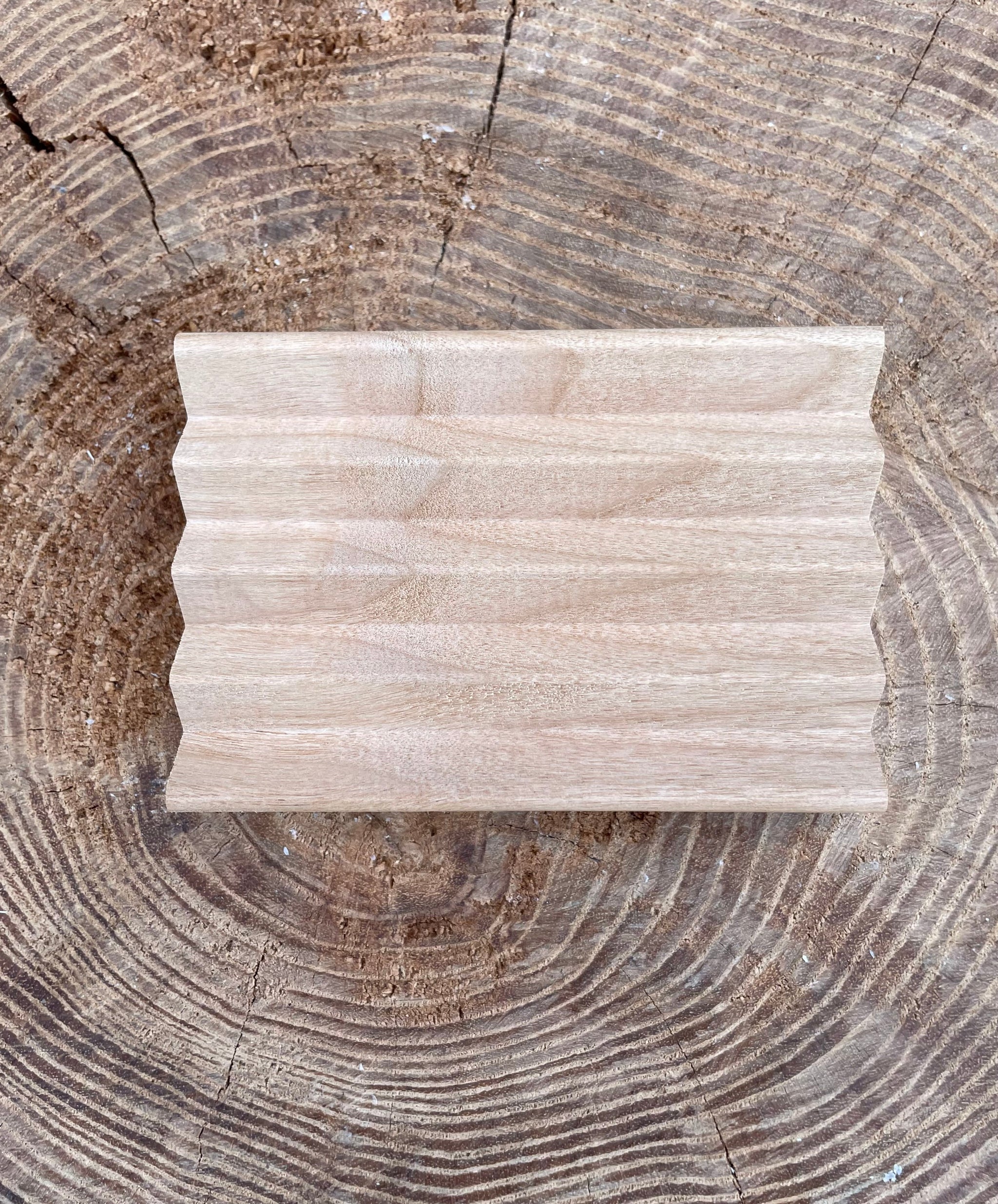 A handcrafted wooden soap dish sits on a rustic tree stump, showcasing natural wood grain.
