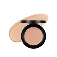 An open compact of light beige cream foundation sits beside a swatch of the product.
