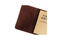 A rustic brown leather notebook cover holds a Field Notes memo book.
