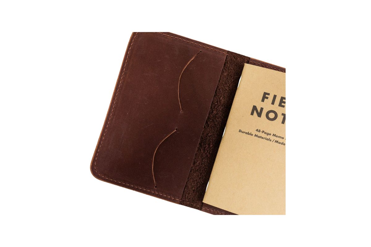 A rustic brown leather notebook cover holds a Field Notes memo book.
