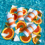 Breathe Naturals deodorant floats with orange slices and coconut in a pool of water, showcasing a refreshing, natural skincare product.
