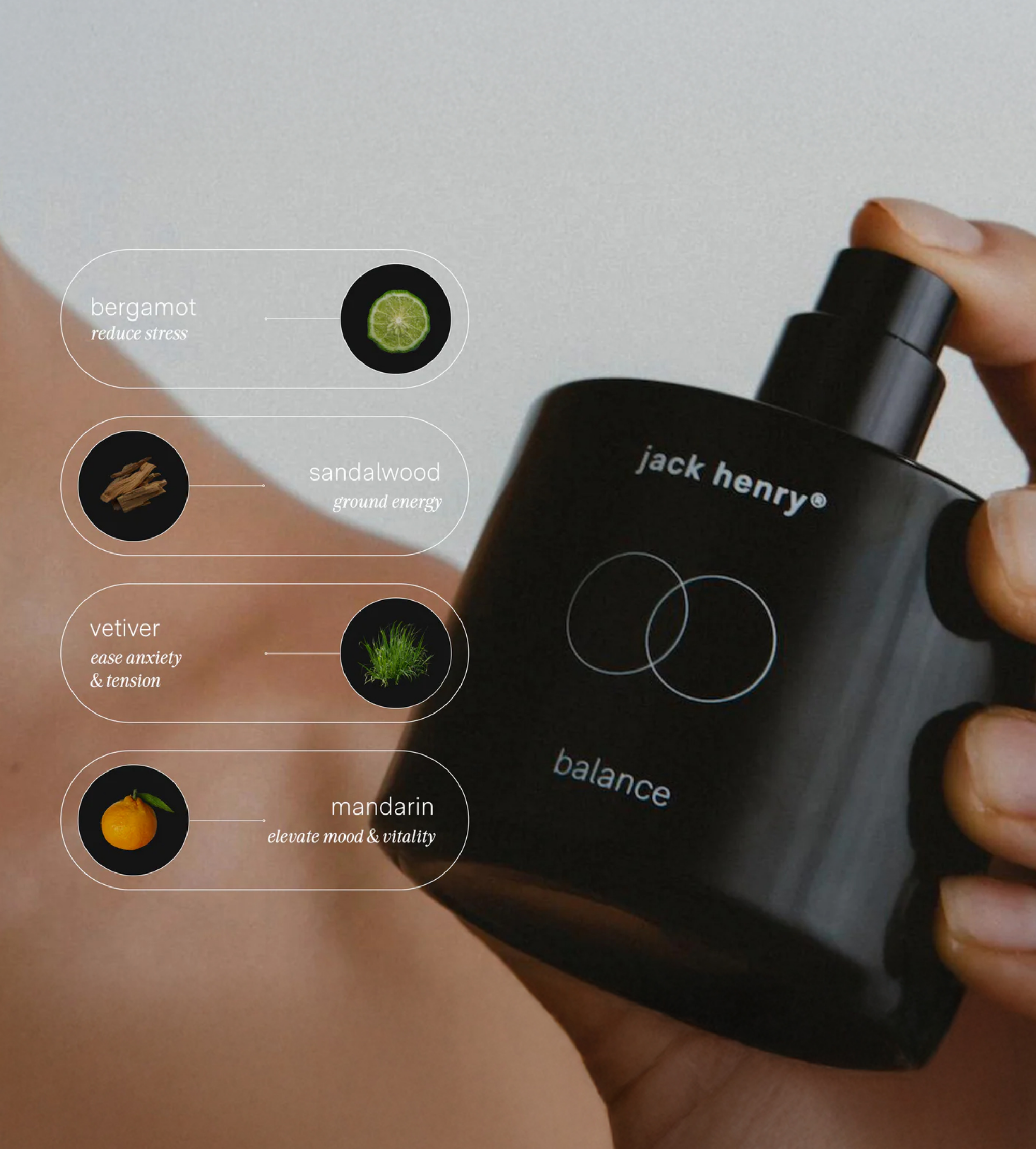 A hand presses the spray nozzle of a Jack Henry Balance fragrance bottle, showcasing its bergamot, sandalwood, vetiver, and mandarin essential oil notes.
