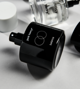 Jack Henry Balance perfume bottle lays on its side next to other fragrance products.
