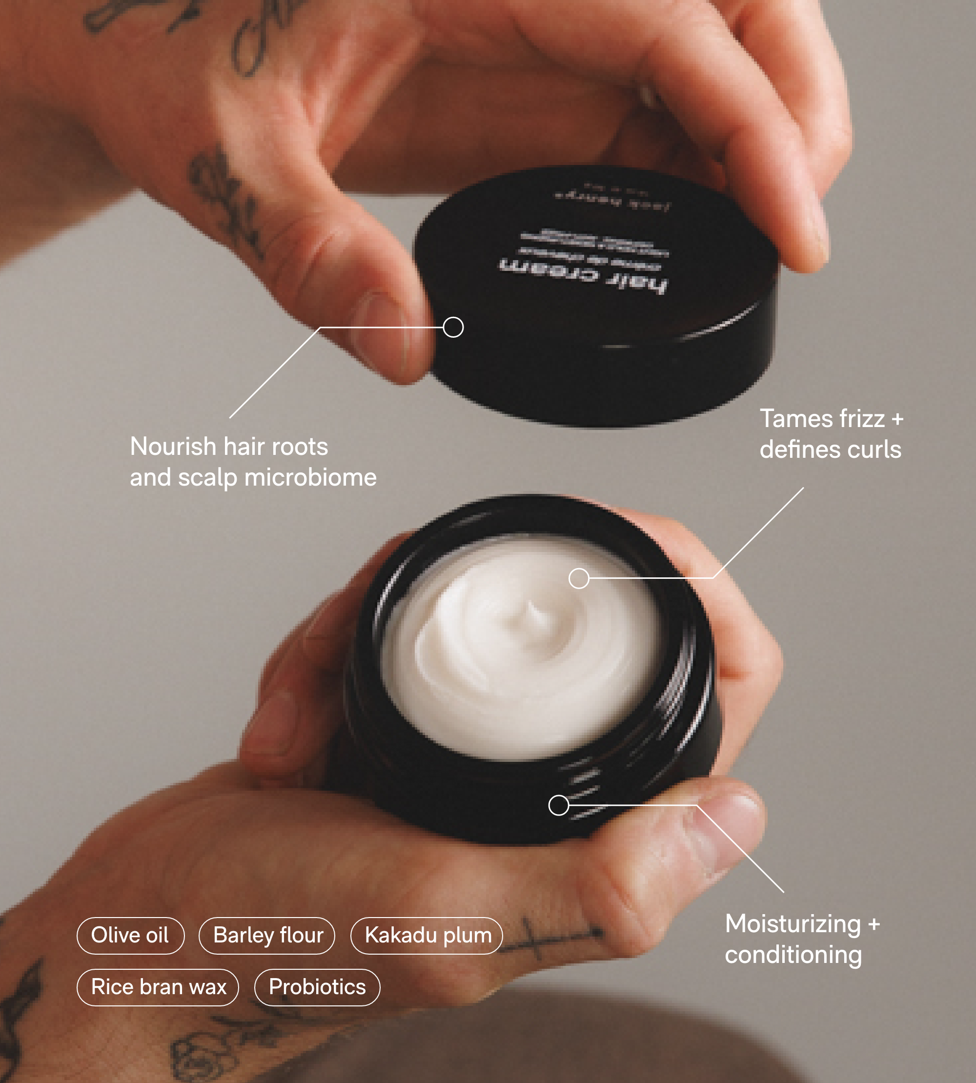 Hands hold open a jar of Jack Henry hair cream, highlighting its moisturizing and curl-defining ingredients like olive oil, barley flour, and probiotics for nourishing hair.
