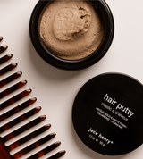 Stylists use Jack Henry Hair Putty from the opened jar for a medium hold and matte finish, while a tortoiseshell comb sits beside the product.
