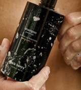 Hands covered in suds hold a bottle of Jack Henry Hinoki Cypress shampoo.
