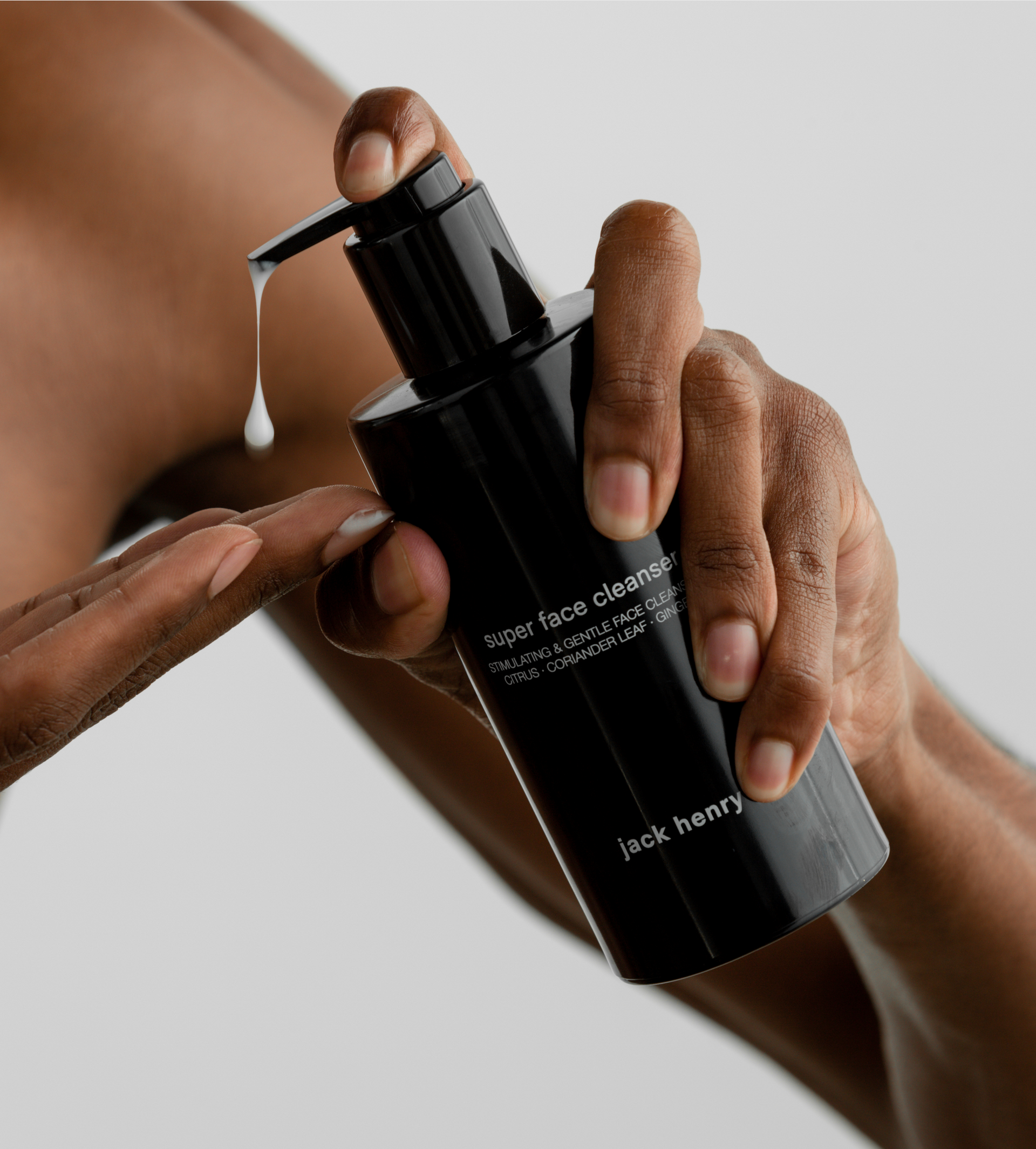 Hands dispense Jack Henry Super Face Cleanser, revealing a drop of the gentle face wash.
