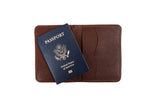 Shows a blue United States passport resting on an open, brown leather passport holder.
