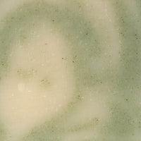 Close-up reveals a handcrafted bar of artisan soap with swirling green and creamy tones.
