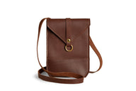 A brown leather crossbody bag with a gold clasp sits on a white background.
